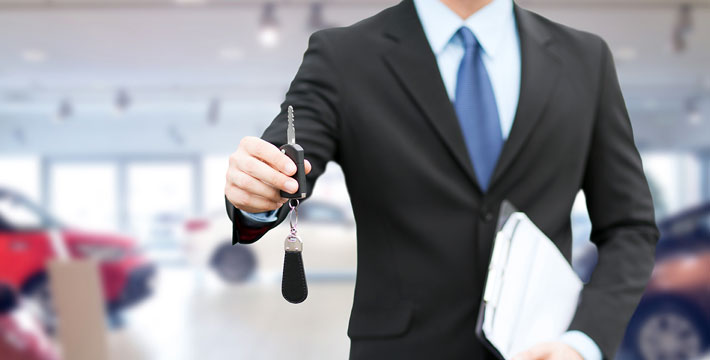 A person in suit and tie holding a set of keys