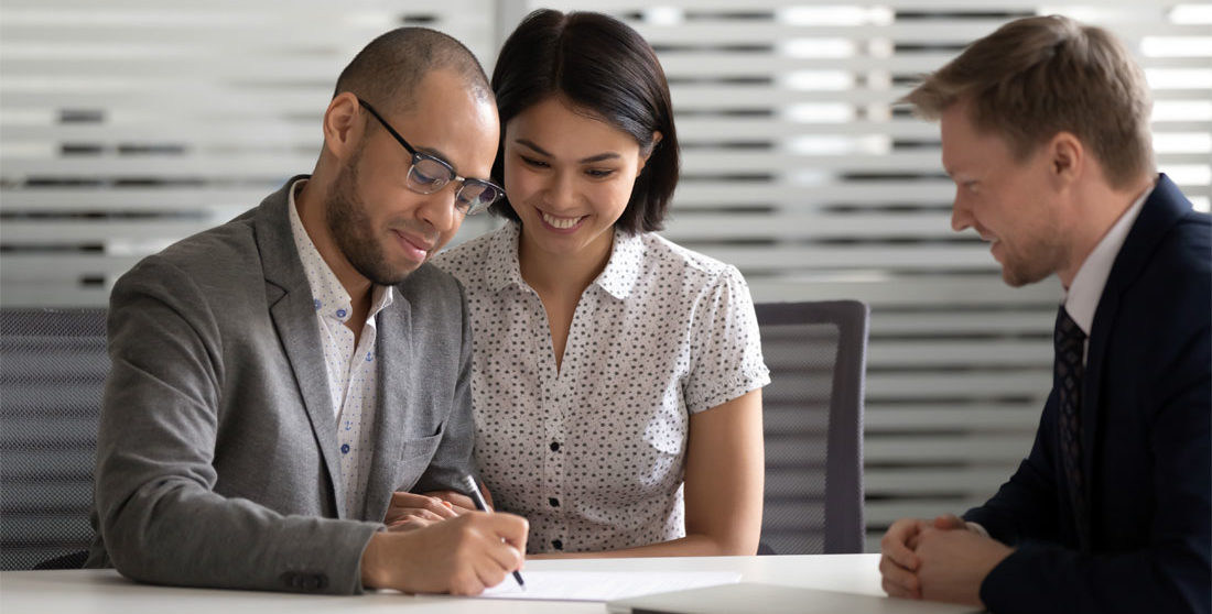 A smiling couple signing an insurance document