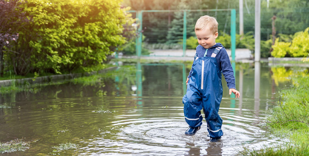 Photo of a child jumping in puddles after heavy rain