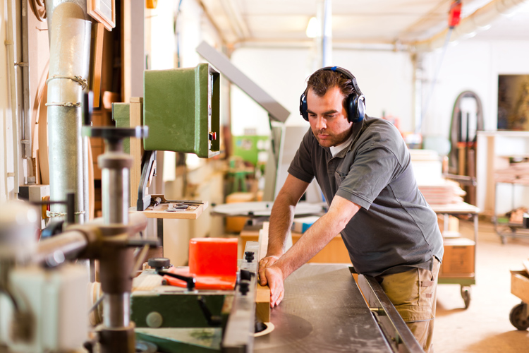 A photo illustrating a potential candidate for workers' compensation insurance in Southeastern MA, a worker using machinery